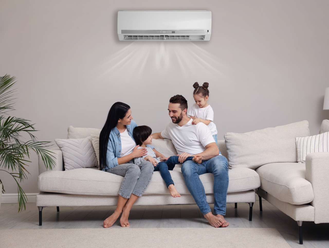 Happy family on sofa in living room. Air conditioner keeping comfortable temperature in room